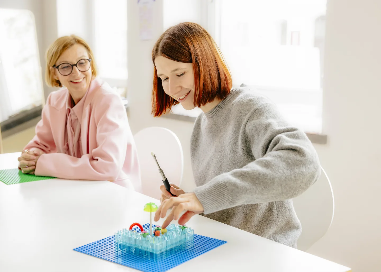Eine Teilnehmerin baut während eines Workshops an einem Modell, eine Kollegin beobachtet.