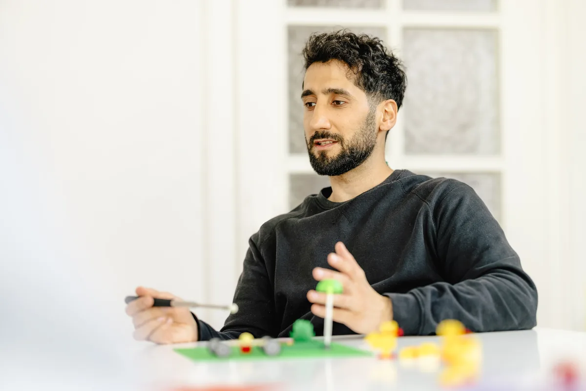Ein Teilnehmer erklärt gestikulierend sein Modell während des Workshops.