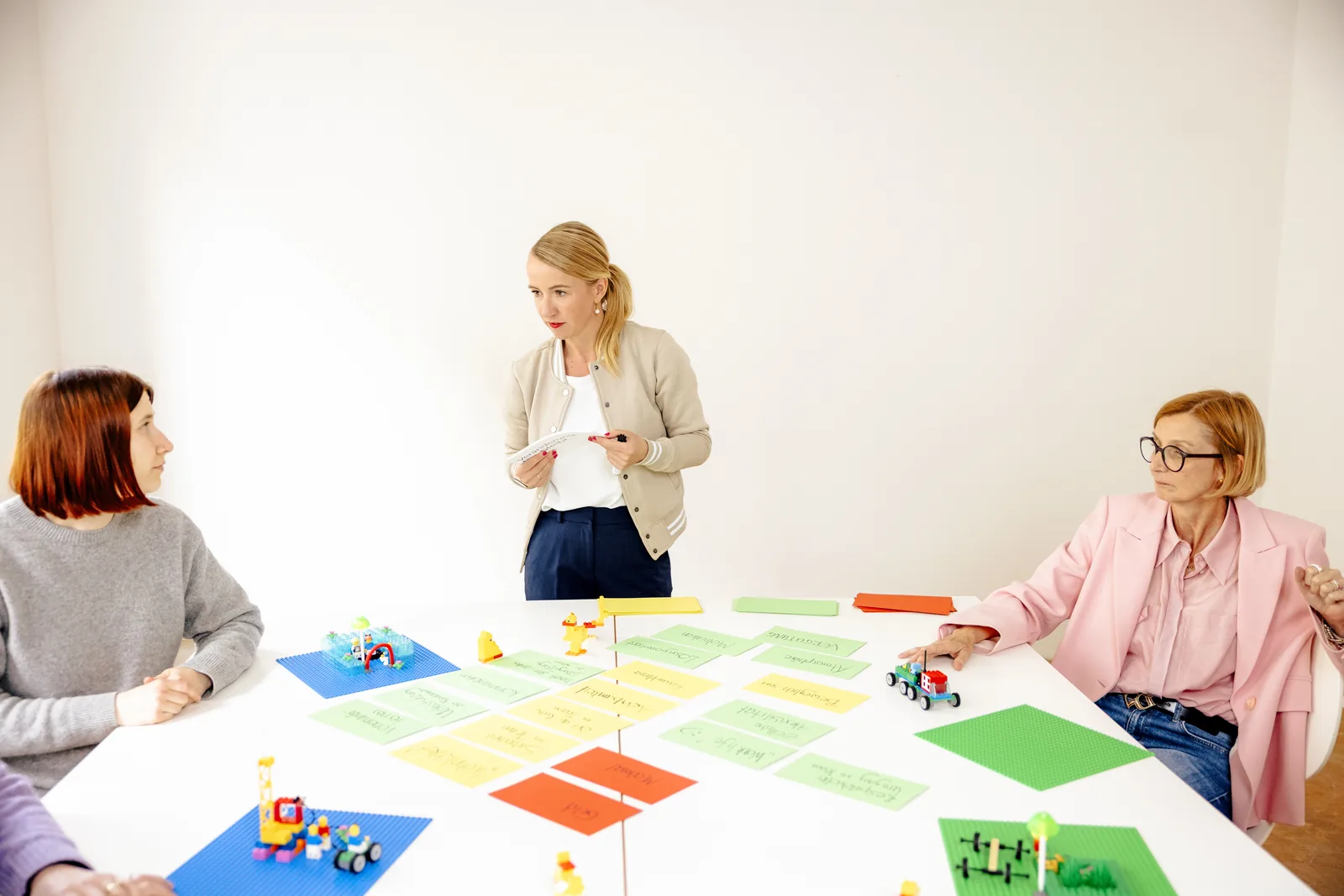 Tanja Petersen moderiert einen Workshop mit Teilnehmerinnen, Modellen und Arbeitskarten auf dem Tisch.